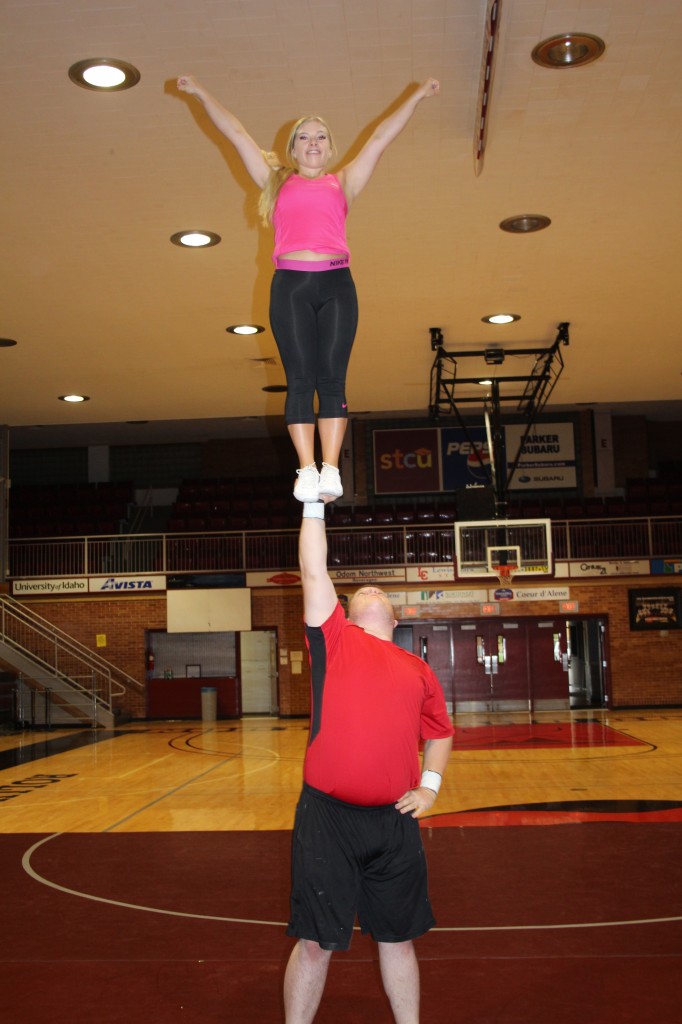 Morgan Nichols holds flyer, Hayley Kaiser in a "cupie" during warmups before tryouts Thursday night.